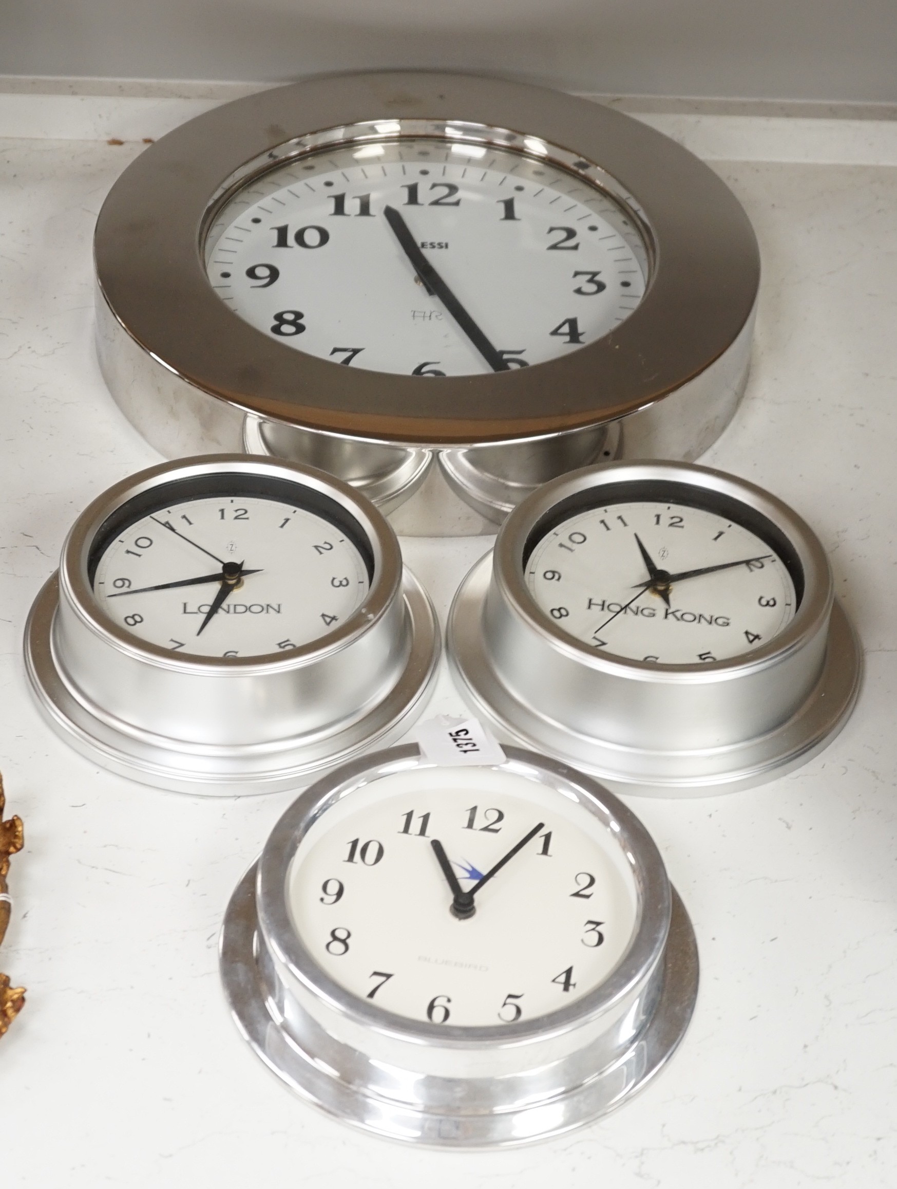 An Alessi wall clock and three similar smaller wall dials